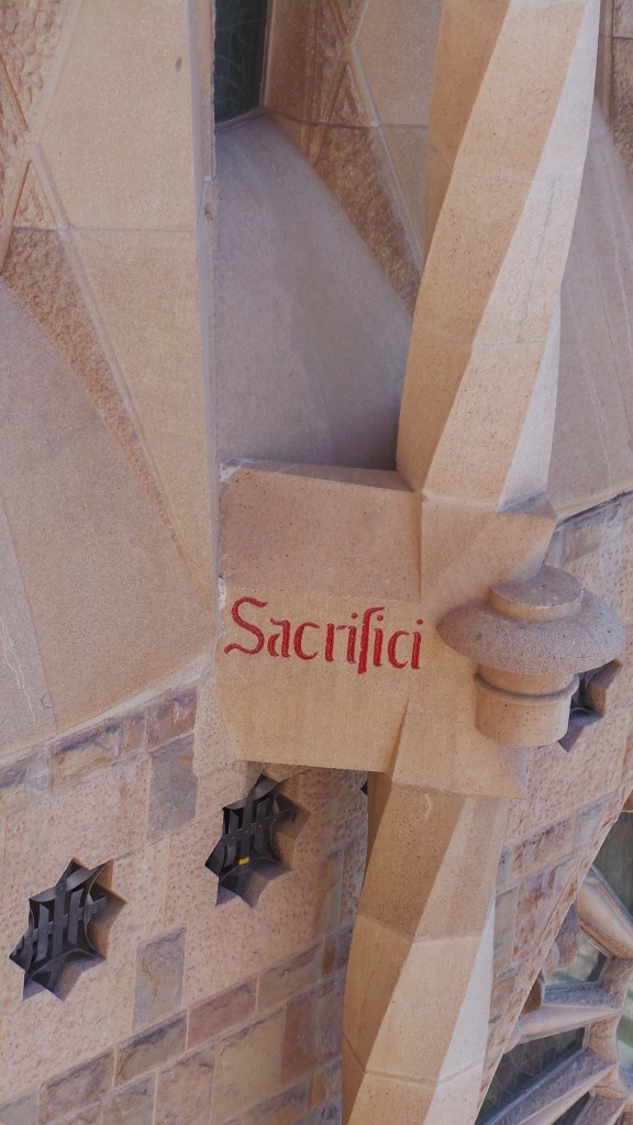 'Sacrifici' or 'Sacrifice' text on the Sagrada Familia exterior